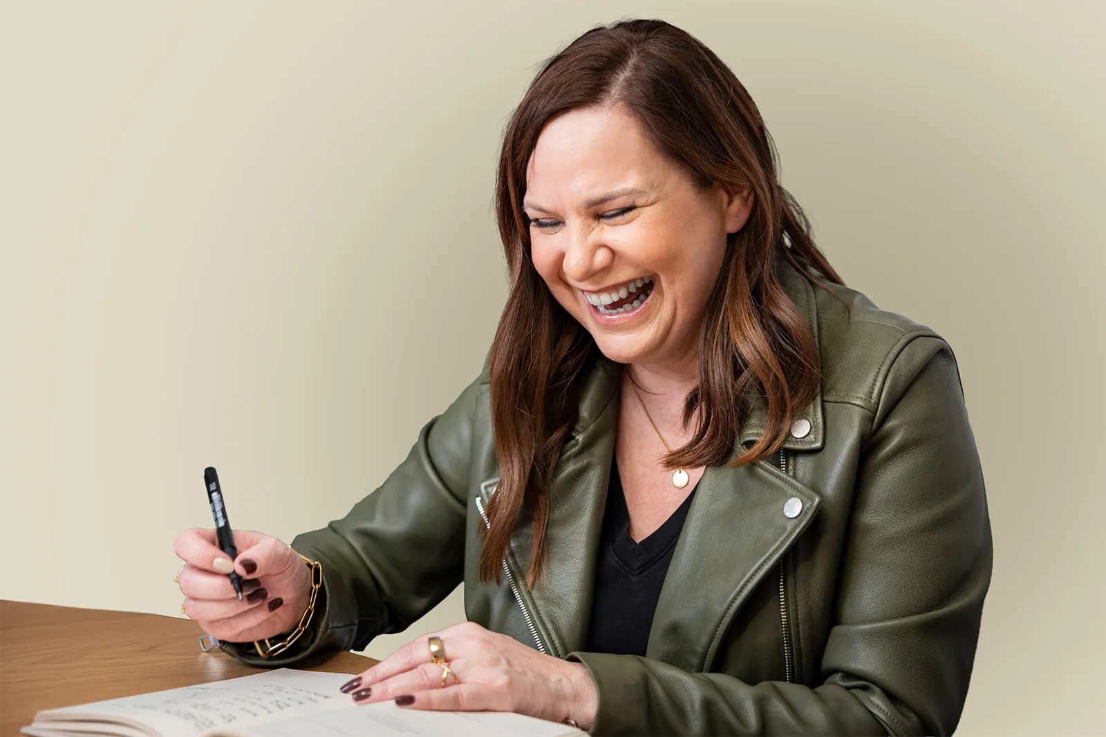 Claudia Lorber lacht beim Schreiben in ihr Notizbuch